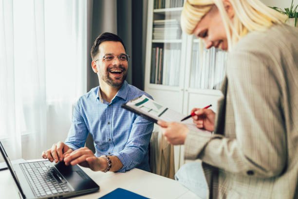 A man and woman laugh together while using a laptop, discussing credit report errors.
